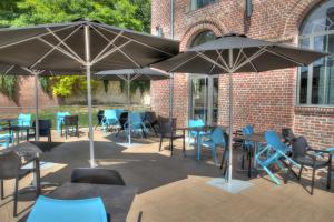 un patio avec des tables, des chaises et des parasols dans l'établissement Hôtel de la Tabletterie, à Méru