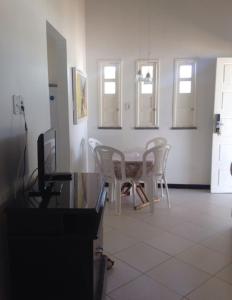 a dining room with a table and white chairs at CHALÉS ENCANTOS DA ILHA in Barra dos Coqueiros