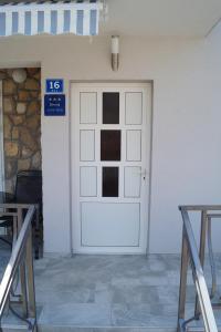 Una puerta blanca en un edificio con un cartel. en Apartment Ivona, en Stomorska