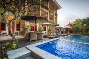 a hotel with a swimming pool with people sitting under umbrellas at Pondok Anyar Hotel in Kuta