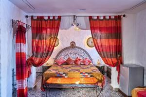 um quarto com uma cama grande e cortinas vermelhas em Dar Yakout em Chefchaouen