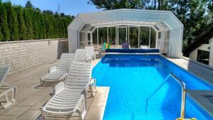 a swimming pool with white chairs and a swimming poolvisor at Pansion Bijela Ruža - a la carte in Ravna Gora
