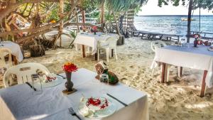 a restaurant on the beach with tables and chairs at Rasdhoo Island Inn Beachfront in Rasdu