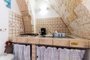 una piccola cucina con lavandino e piano cottura di la casa di Daisy a Carloforte