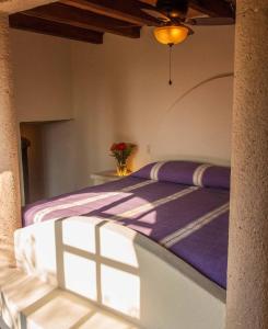 a bedroom with a bed with a purple comforter at HEVEN Residence in Zipolite