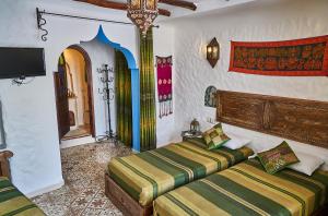 Un dormitorio con dos camas y un televisor en la pared. en Dar Yakout, en Chefchaouen
