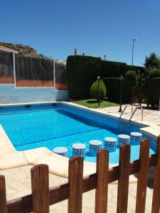 a swimming pool with four tables and a fence at Quevoy in Alcañiz