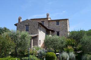 un gran edificio de piedra en una colina con árboles en Re Artù Assisi Country Lifestyle, en Asís