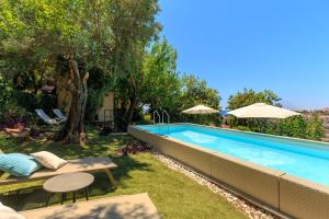 a swimming pool in a yard with chairs and umbrellas at Villa Tranquillity XII in Dubrovnik