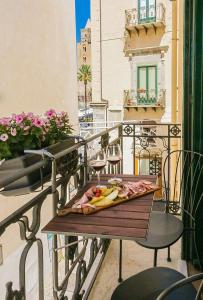 einen Teller mit Essen auf einem Tisch auf einem Balkon in der Unterkunft Le suite del corso in Cefalú