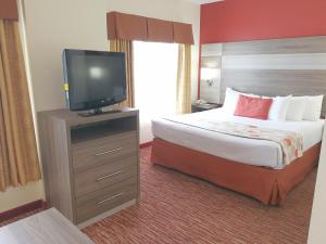 a hotel room with a bed and a flat screen tv at Hawthorn Suites Irving DFW South in Irving