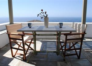 una mesa y sillas en un balcón con vistas al océano en Aegean Panorama in Tinos, en Tinos