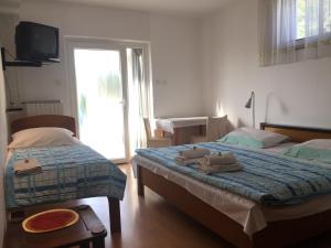 een slaapkamer met 2 bedden, een tv en een raam bij Tourist Rooms Sajovic in Postojna
