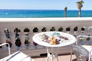 a table with a plate of food on a balcony with the ocean at Hotel Villa La Brise in Sanremo
