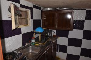 a kitchen with a sink and a checkered wall at Petra Cottage in Al Ḩayy