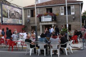 un grupo de personas sentadas en mesas frente a un edificio en Hotel Victorino, en Silleda