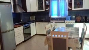 eine Küche mit weißen Schränken sowie einem Tisch und Stühlen in der Unterkunft Zogaj Guesthouse in Ksamil