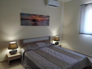 a bedroom with a bed and two night stands with lamps at SunStone Court in St Paul's Bay