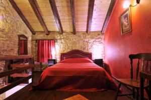 a bedroom with a red bed in a stone wall at Georgio's V Chalet Kalavrita in Kalavrita