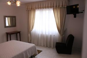 1 dormitorio con 1 cama y ventana con silla en Hotel Victorino, en Silleda