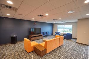 a waiting room with orange chairs and a television at Gundersen Hotel & Suites in La Crosse