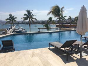 a swimming pool with two chairs and an umbrella at Amazing Vista Coral Condo in La Paz