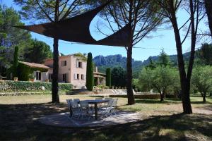 una mesa y sillas en un patio con una casa en La Bastide de la Provence Verte, chambres d'hôtes, en La Roquebrussanne