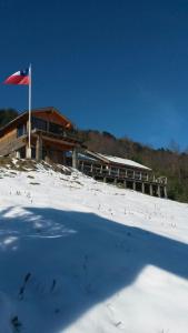 a building in the snow with a flag on it at Cabaña Alto Pucón in Pucón