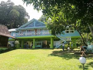 a green house with people sitting in the yard at Kapitan Lodge in Port Dickson