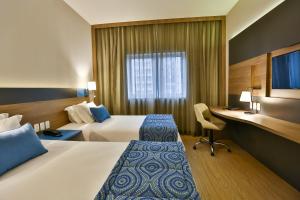 a hotel room with two beds and a desk at Hilton Garden Inn Santo Andre in Santo André