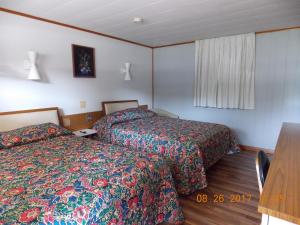 a hotel room with two beds and a table at Melody Motor Lodge in Connellsville