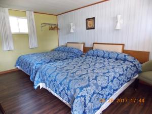 1 dormitorio con 2 camas y ventana en Melody Motor Lodge, en Connellsville