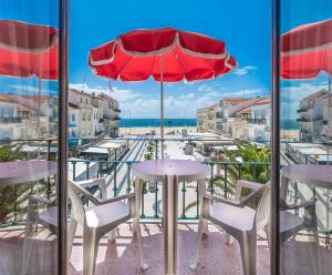 un patio con mesa, sillas y sombrilla en Solar dos Carvalhos - Apartamentos de Turismo en Nazaré