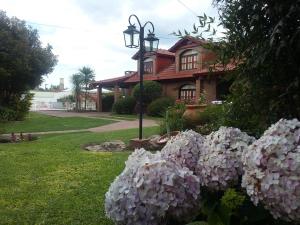 une maison avec des fleurs roses devant elle dans l'établissement Cabañas La Aldea, à Villa Carlos Paz