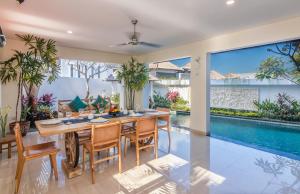 een eetkamer met een tafel en stoelen en een zwembad bij Villa Allamanda by Kubu GWK in Jimbaran