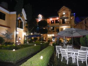 Hotel Farah في Nuevo San Juan Parangaricutiro: طاولة وكراسي ومظلة أمام المبنى