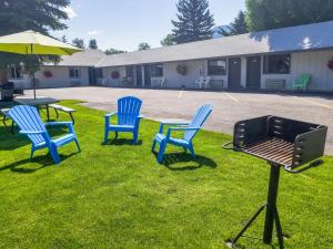 three blue chairs and a grill in the grass at Alpine Motel in Jackson