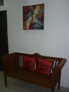 a wooden couch with two red pillows under a painting at Hotel Paka INN in Paka