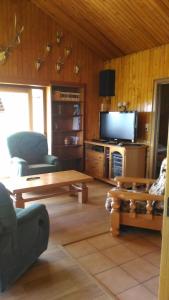 uma sala de estar com uma televisão, um sofá e uma mesa em Gite des 3 bouleaux em Robelmont
