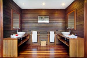 a bathroom with two sinks and wooden walls at Gangehi Island Resort & Spa in Gangehi