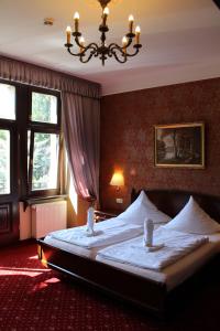 a bedroom with a large bed with a chandelier at Schlosshotel Stecklenberg in Thale