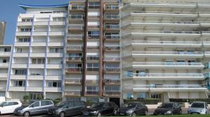 un condominio alto con auto parcheggiate di fronte di Studio Front Mer a Le Touquet-Paris-Plage