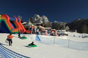 un grupo de personas jugando en la nieve en una estación de esquí en Hotel Principe, en Selva di Cadore
