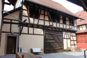 um edifício antigo com uma porta de madeira e uma mesa em Gîte de l'ours grognon em Dambach-la-Ville