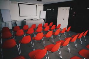 una sala de conferencias con sillas rojas y una pantalla en Le Nove Hotel, en Nove