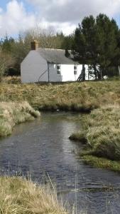ein Haus auf einem Feld neben einem Fluss in der Unterkunft Keepers Cottage in Forsinain + 2 Fotos