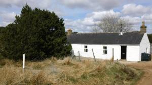 ein weißes Haus mit einem schwarzen Dach in der Unterkunft Keepers Cottage in Forsinain