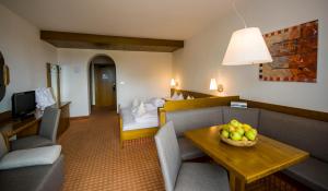 Habitación de hotel con sofá y mesa con un bol de fruta en Christophs Hotel, en Scena