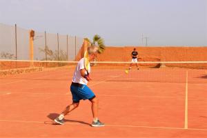 two men playing tennis on a tennis court at Hotel De Charme Les 3 Chameaux 4 étoiles in Mirleft