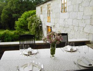 una mesa con platos y un jarrón de flores. en Fervenza Casa Grande & Restaurante, en Reguengo